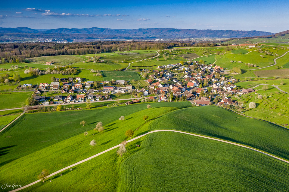 Luftaufnahme des Dorfes Arisdorf mit grünen Feldern und Bauernhöfen im Frühling, Baselland Schweiz – Jan Geerk Fotograf Basel