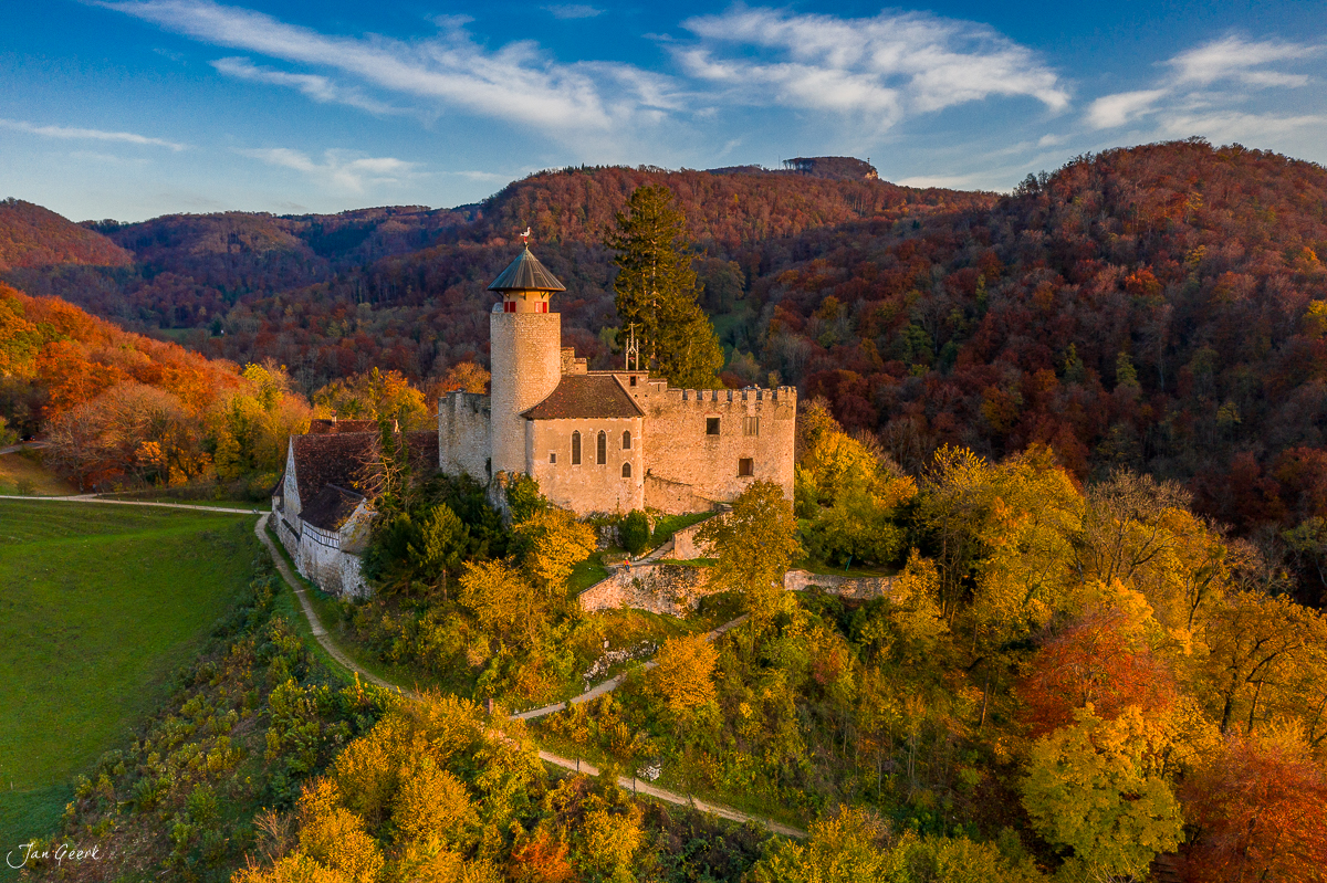 Schloss Reichenstein herbstlich umgeben von rot-orangefarbenen Wäldern in der Birseck, Baselland Schweiz – Jan Geerk Fotograf Basel