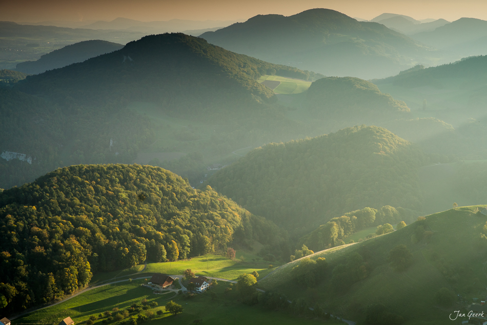 Herbstliche Berglandschaft im Bölchen mit Waldtälern und Bauernhof bei goldenem Licht – Jan Geerk Fotograf Basel Schweiz