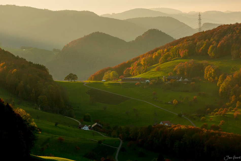 Herbstliche Berglandschaft Dornach mit grünen Wiesen, golden gefärbten Wäldern und Nebel über den Jurahöhen in der Nordwestschweiz – Jan Geerk Fotograf Basel