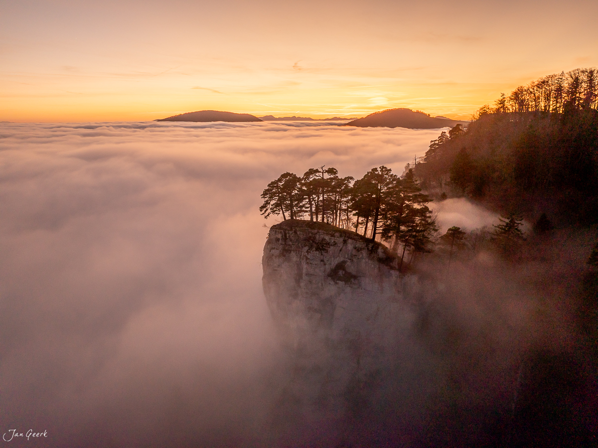 Felsenvorsprung mit Bäumen über Nebelmeer am Ankenballen herbstlich golden beleuchtete Berglandschaft Baselland Schweiz Jan Geerk Fotograf Basel