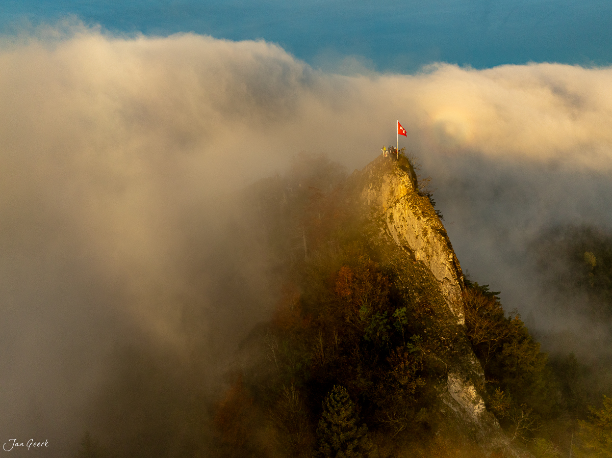 Felsengipfel mit Schweizer Flagge auf der Bölchenfluh in Herbstnebel, Baselland Nordwestschweiz Schweiz – Jan Geerk Fotograf Basel