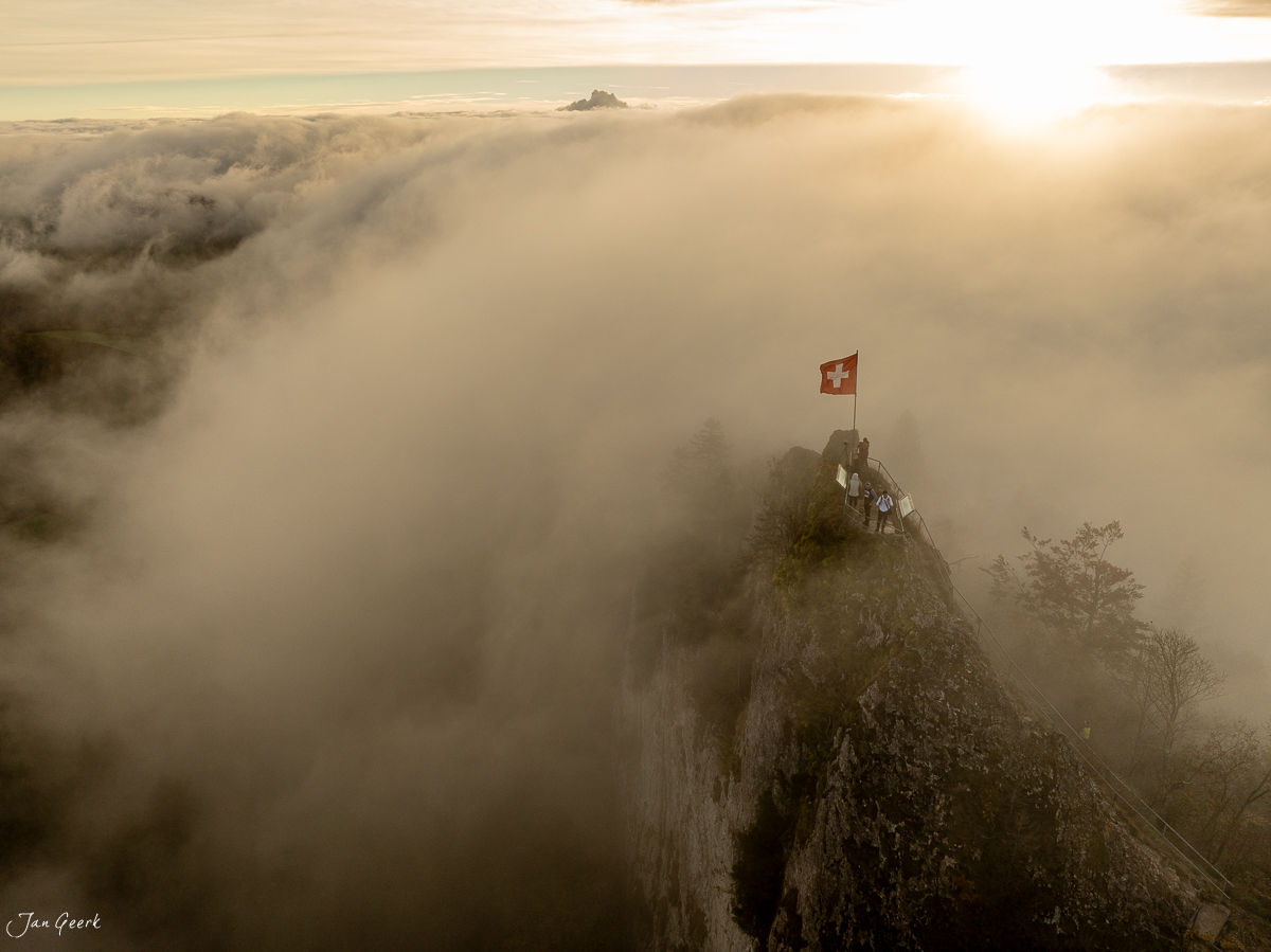 Schweizer Flagge auf Felsenspitze über Nebelwelle Bölchenfluh Herbstlichtstimmung Baselland Schweiz – Jan Geerk Fotograf Basel