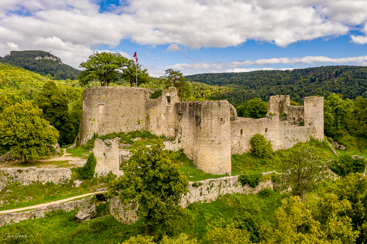 Mittelalterliche Burgruine mit Schweizer Flagge in grüner Landschaft, Sommer, Baselland Schweiz – Jan Geerk Fotograf Basel