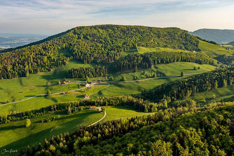 Luftaufnahme Langenbruck mit Bergwald und grünen Wiesen, Frühlingslicht, Baselland Schweiz – Jan Geerk Fotograf Basel