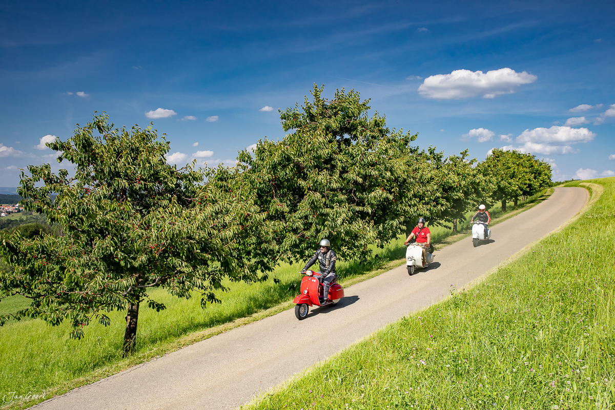 Vespa-Fahrer auf Landstraße im Baselbiet Sommertag grüne Wiesen Schweiz Jan Geerk Fotograf Basel