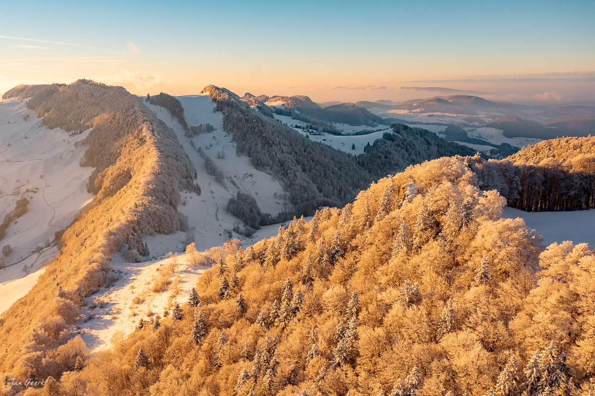 Schneebedeckte Waldweid-Hügel im goldenen Morgenlicht, verschneite Tannen, Baselland Schweiz – Jan Geerk Fotograf Basel