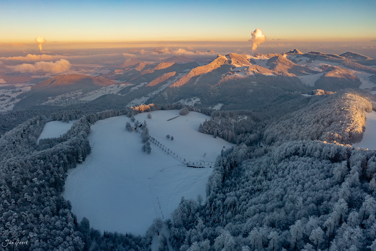 Gefrorener See Waldweid im Schnee umgeben von verschneiten Wäldern und Bergen bei Sonnenaufgang in der Schweiz – Jan Geerk Fotograf Basel