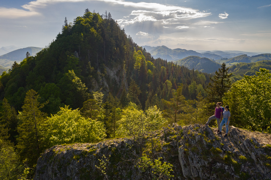 Wanderer auf Felsvorsprung mit Blick auf Belchen Bergwald Frühling Baselland Schweiz Jan Geerk Fotograf Basel