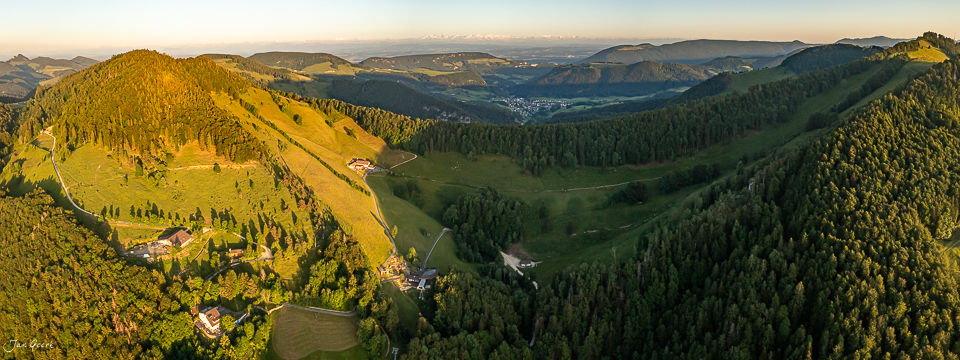 Luftaufnahme Chellechöpfli mit grünen Wiesen, Wäldern und Bergpanorama im goldenen Sonnenlicht, Baselland Schweiz – Jan Geerk Fotograf Basel