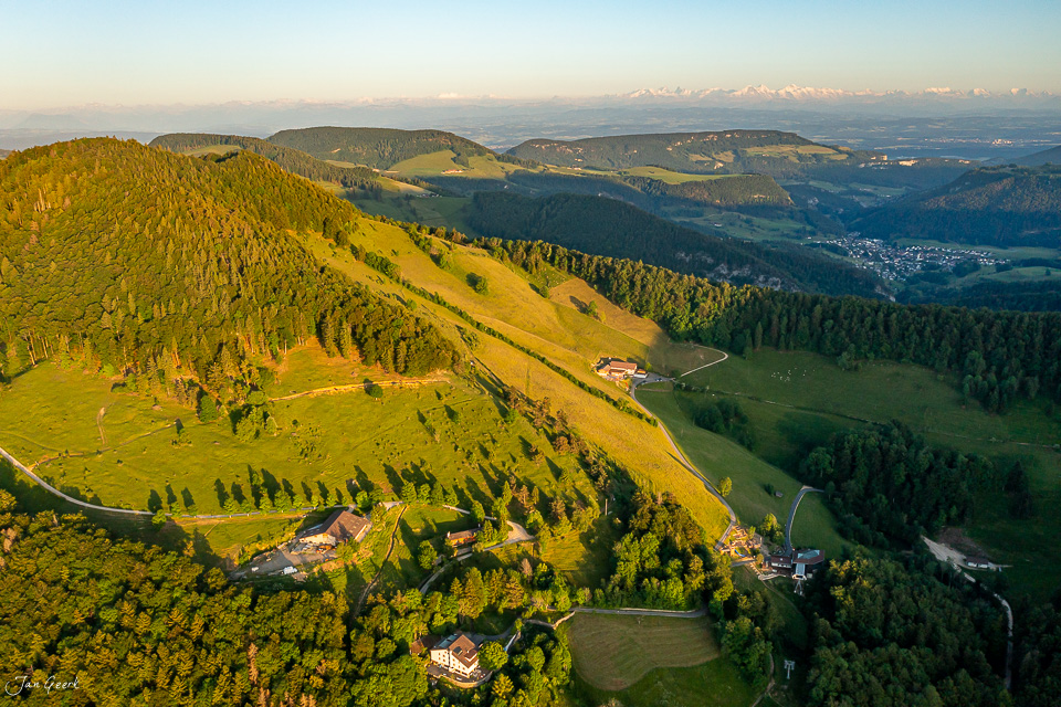 Luftaufnahme Chellechöpfli mit grünen Wiesen, Wäldern und Alpenpanorama im Sommer – Jan Geerk Fotograf Basel Schweiz