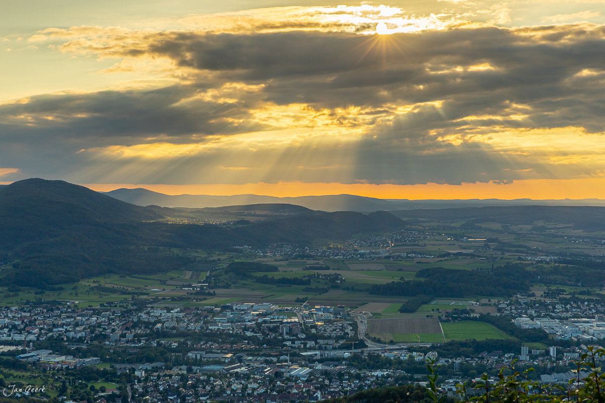 Panoramablick über Gempen bei Sonnenuntergang, grüne Hügellandschaft mit Siedlungen und dramatischem Himmel, Nordwestschweiz – Jan Geerk Fotograf Basel