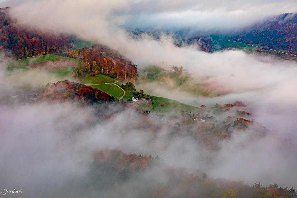 Neblige Herbstlandschaft mit grünen Hügeln und herbstlich gefärbtem Wald auf der Gisliflue in der Nordwestschweiz – Jan Geerk Fotograf Basel