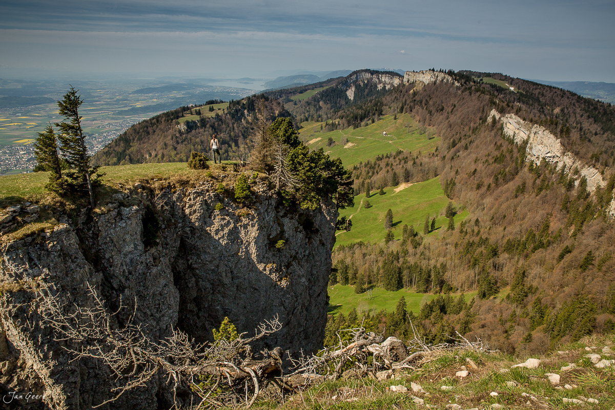 Wanderer auf Felsklippe mit Blick über grüne Jurahügel und Aare-Schlaufe bei Altreu im Frühling, Schweiz – Jan Geerk Fotograf Basel