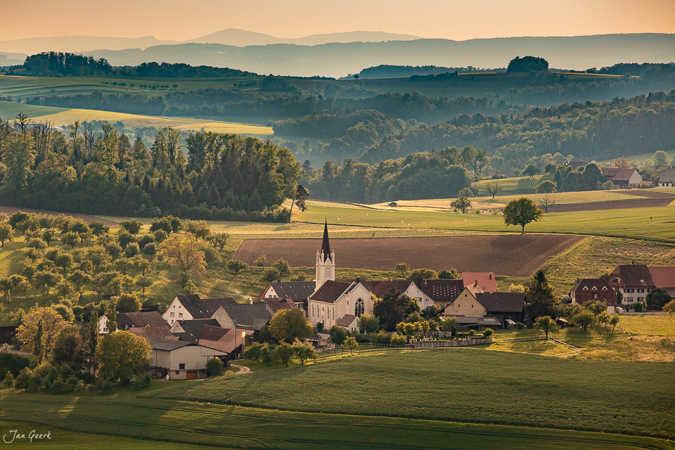 Dorfkirche Kilchberg im Baselland mit Feldern und Wäldern bei Kantlicht Schweiz Jan Geerk Fotograf Basel
