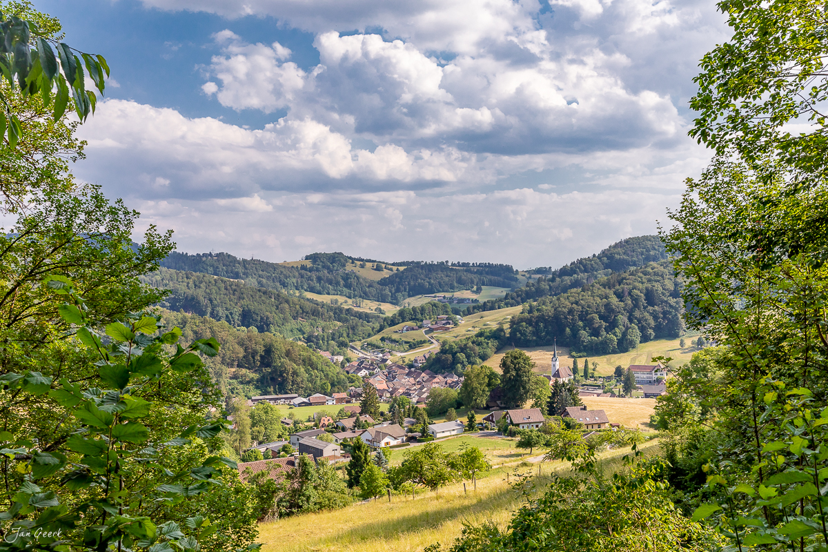 Bergdorf Langenbruck im Baselbiet mit grünen Hügeln, Feldern und Kirchturm im Sommer – Schweiz Jan Geerk Fotograf Basel
