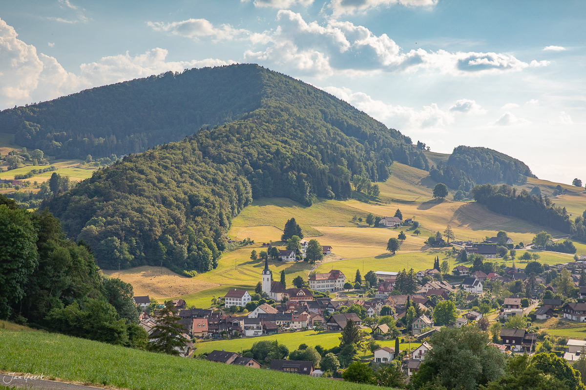 Idyllisches Alpendorf Langenbruck mit grünen Wiesen und bewaldeten Bergen im Sommer, Baselland Schweiz – Jan Geerk Fotograf Basel