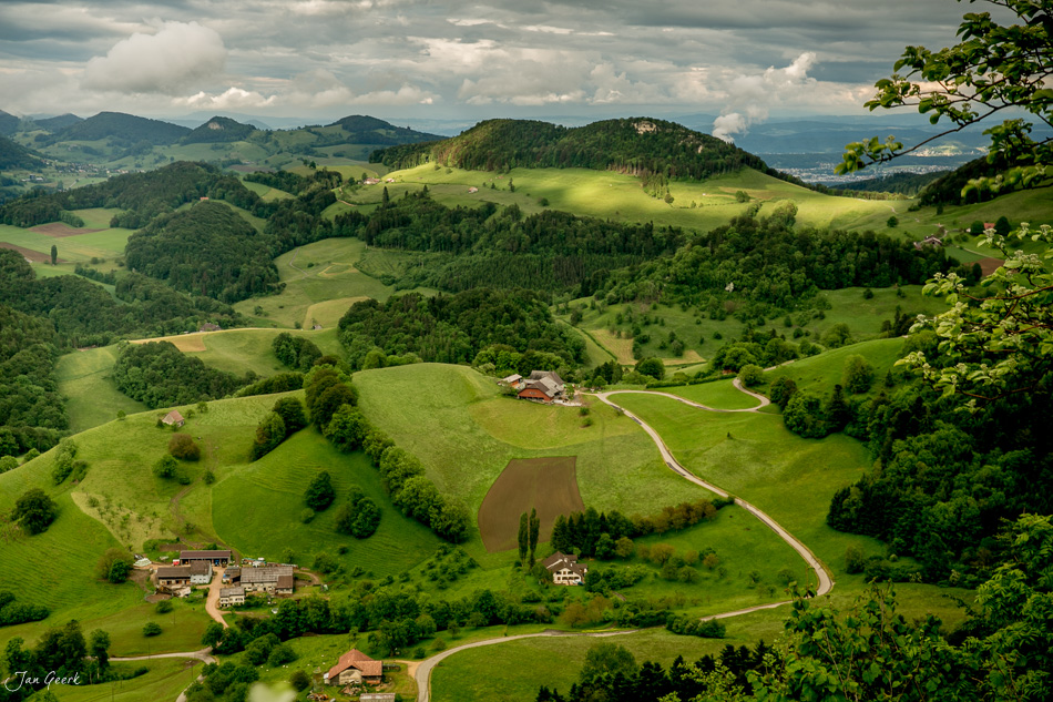 Luftaufnahme Bölchenregion mit grünen Weiden, Wäldern und Bauernhöfen bei Gewitterstimmung im Frühling, Baselland Schweiz – Jan Geerk Fotograf Basel