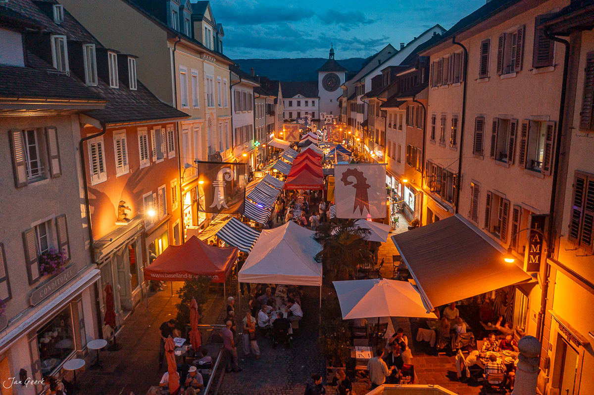 Lange Tafel Fest in Laufen mit illuminierten Zelten und Häusern bei Dämmerung, Baselland Schweiz – Jan Geerk Fotograf Basel