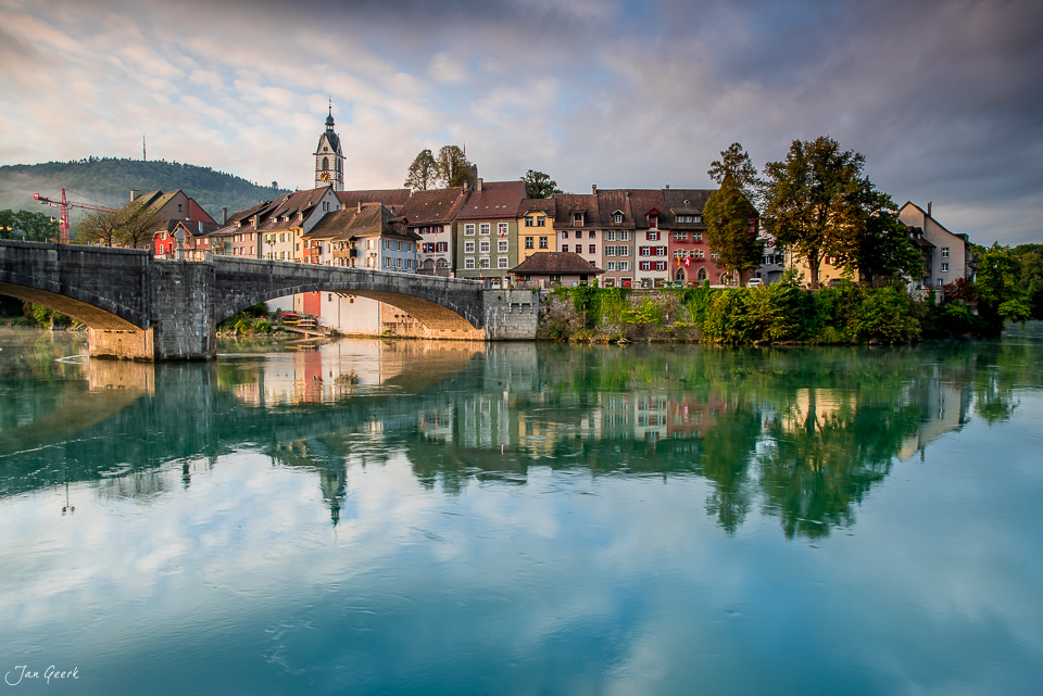 Altstadt Laufenburg mit Rheinbrücke und farbigen Häusern spiegelt sich im ruhigen Fluss, Herbstlicht, Schweiz – Jan Geerk Fotograf Basel