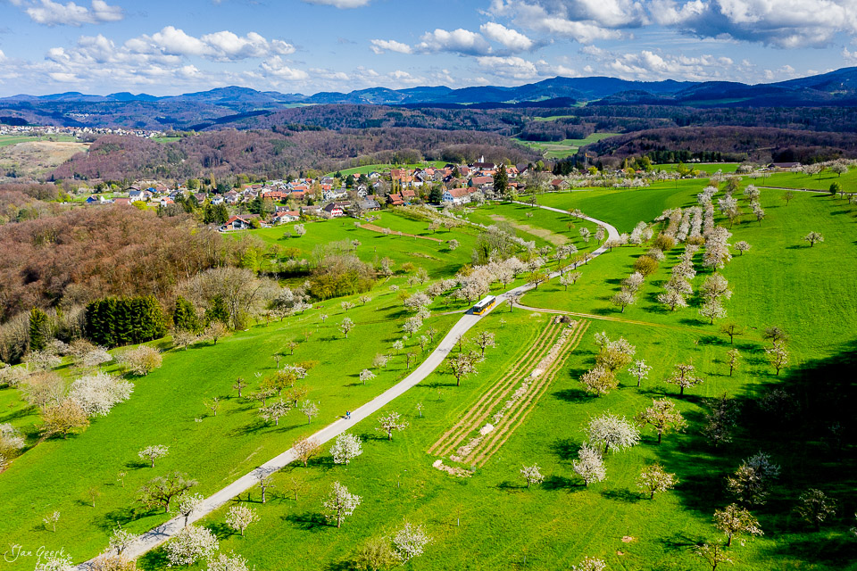 Luftaufnahme Nuglar-St. Pantaleon mit blühenden Kirschbäumen, grünen Wiesen und Dorfansicht im Frühling, Nordwestschweiz – Jan Geerk Fotograf Basel