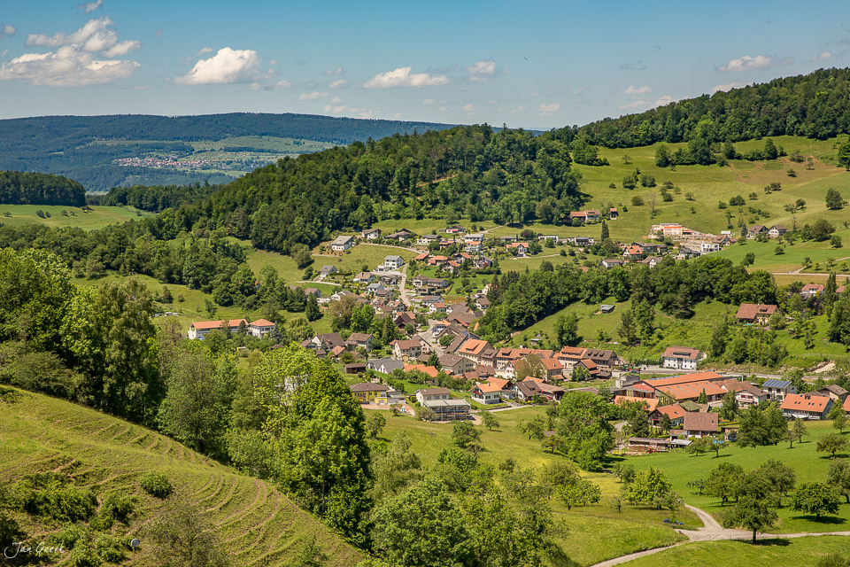 Luftaufnahme des Dorfes Nunningen mit grünen Wiesen, Wäldern und traditionellen Häusern im Sommer, Baselland Schweiz – Jan Geerk Fotograf Basel