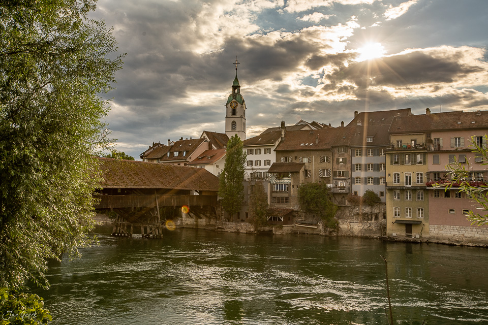 Historische Holzbrücke über die Aare in Olten mit Kirchturm und Altstadt an sommerlichem Tag mit dramatischem Himmel – Jan Geerk Fotograf Basel