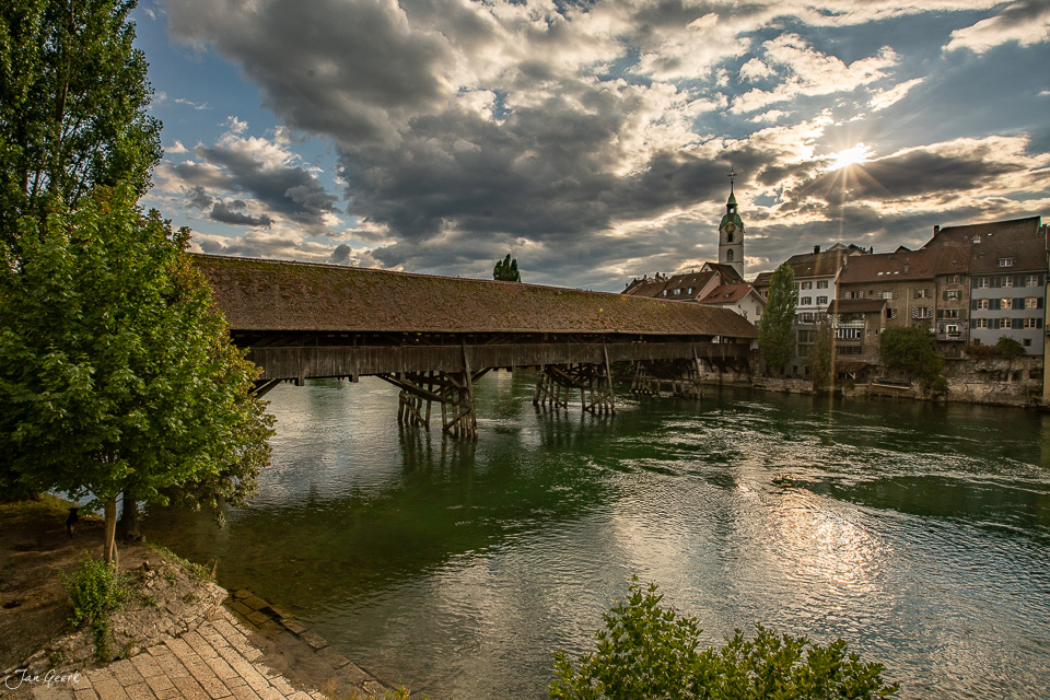 Holzbrücke über die Aare in Olten mit Kirche im Hintergrund, bewölkte Sommerstimmung, Nordwestschweiz – Jan Geerk Fotograf Basel