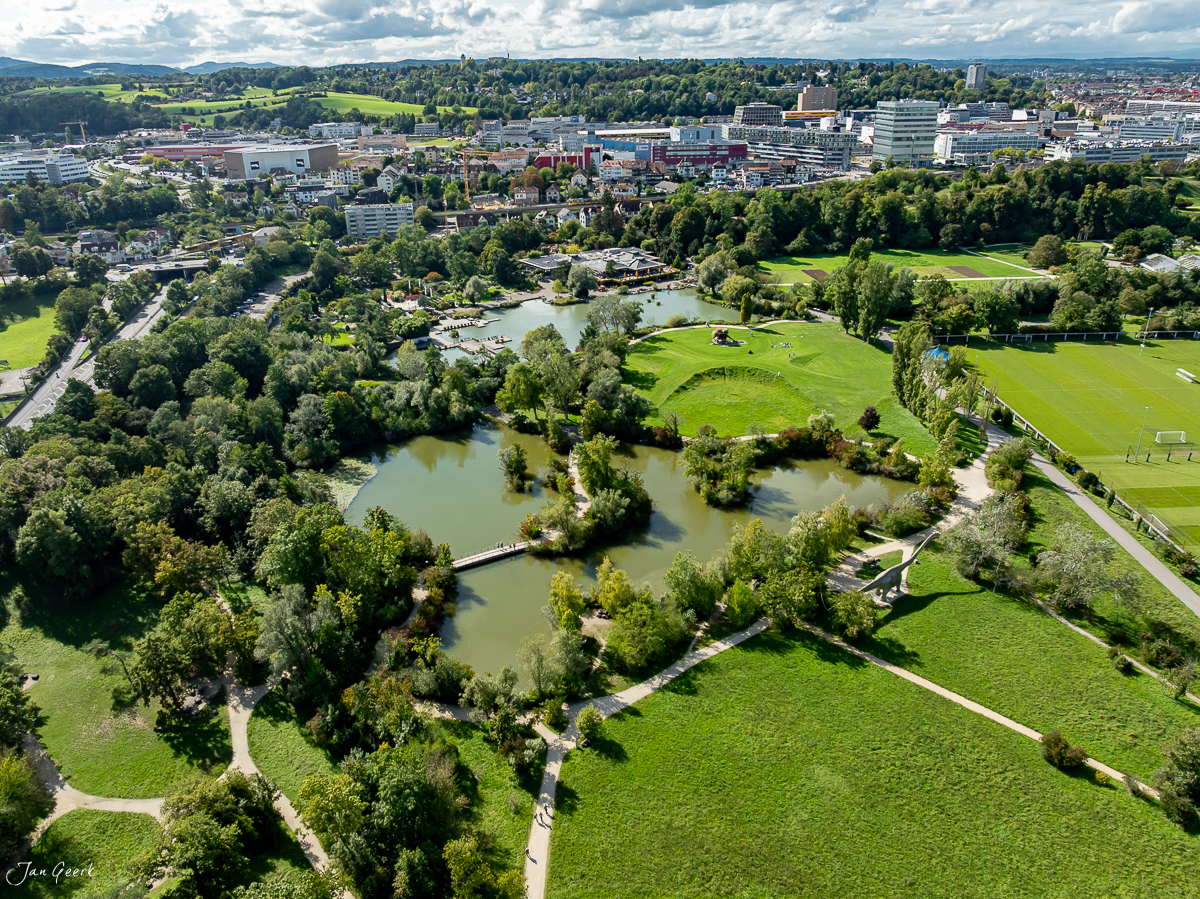 Luftaufnahme Park im Grünen Münchenstein mit Gewässer, grünen Wiesen und Stadtsilhouette, Sommerlicht Baselland Schweiz – Jan Geerk Fotograf Basel