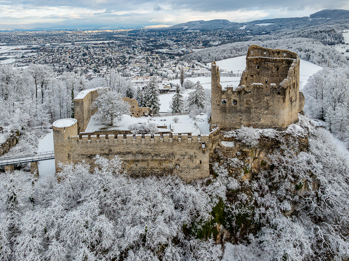 Ruine Pfeffingen im Schnee mit Winterlandschaft, Luftaufnahme des Burgenlands in der Schweiz – Jan Geerk Fotograf Basel