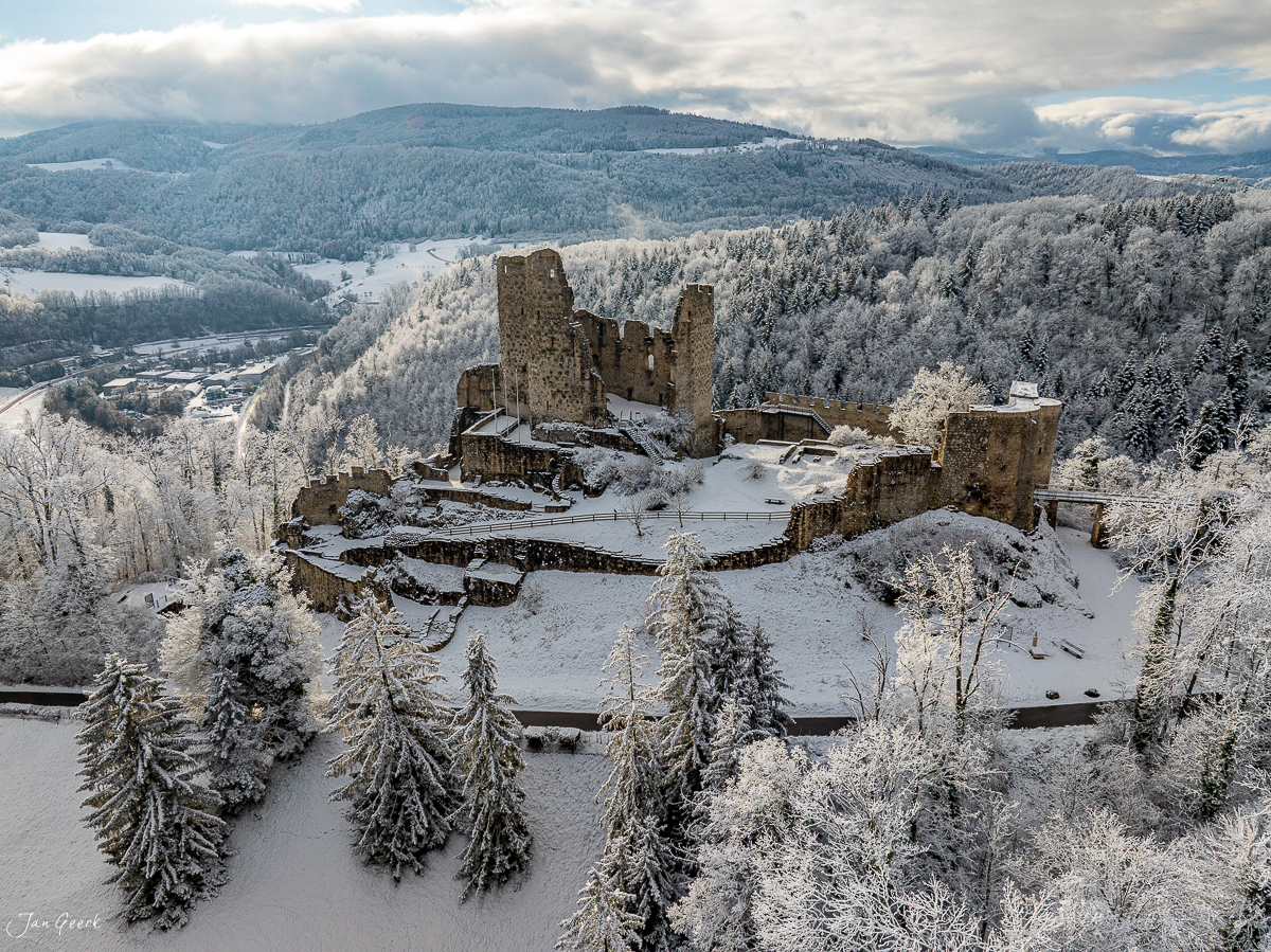 Burgruine Pfeffingen im Schnee mit verschneiten Wäldern und Hügeln, Winteraufnahme aus der Luft, Baselland Schweiz – Jan Geerk Fotograf Basel