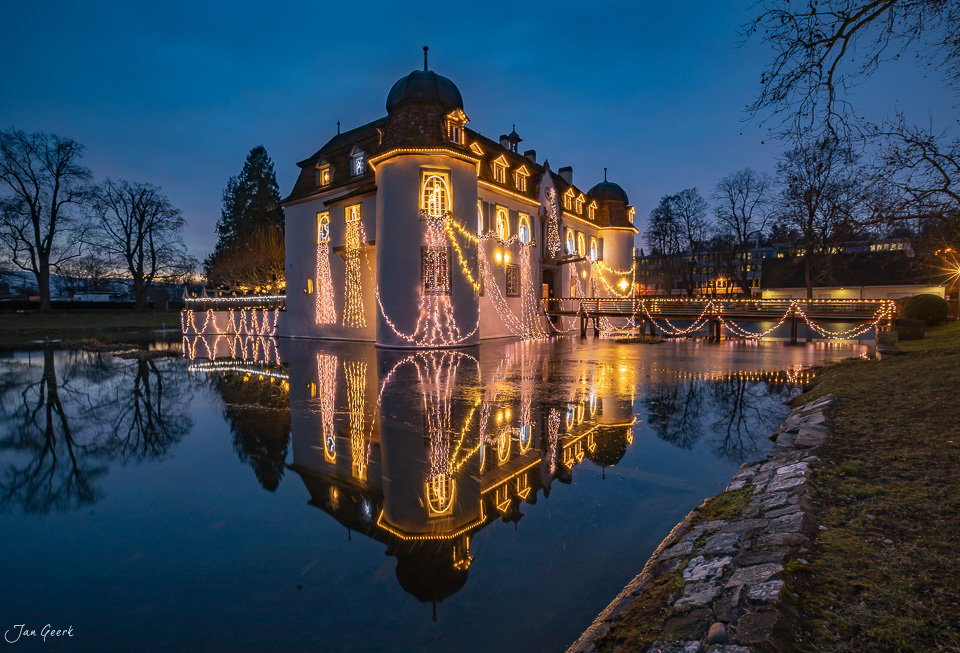 Schloss Bottmingen mit Weihnachtsbeleuchtung nachts, Spiegelung im Wasser, Winter in der Schweiz – Jan Geerk Fotograf Basel