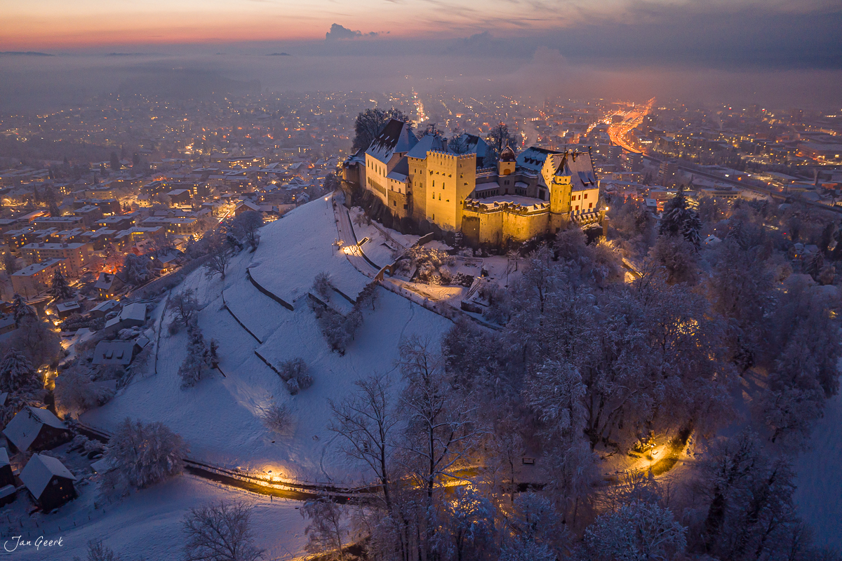 Schloss Lenzburg bei Sonnenuntergang im Winter, schneebedeckte Landschaft mit beleuchteter Stadt, Nordwestschweiz – Jan Geerk Fotograf Basel