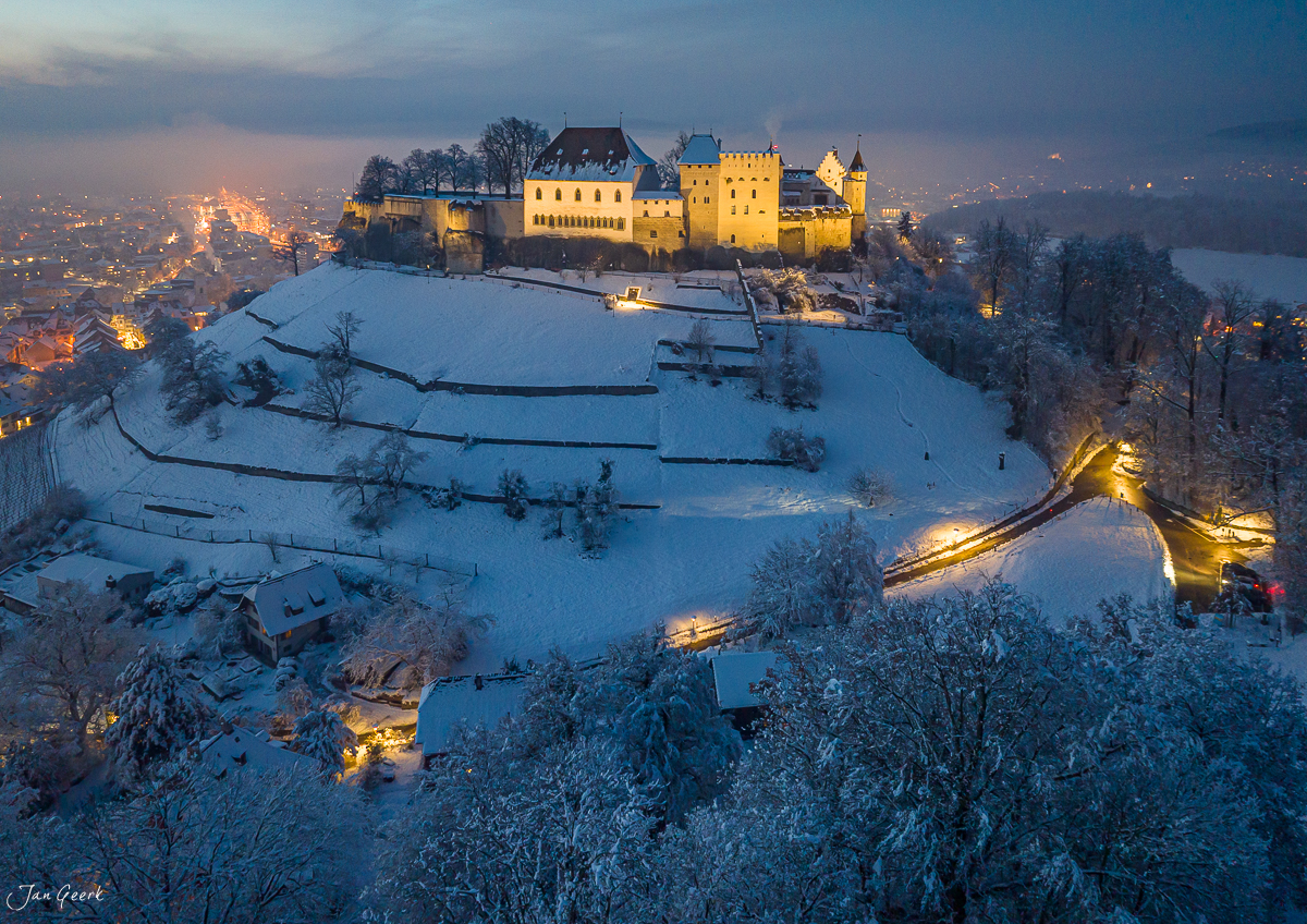 Schloss Lenzburg im Schnee bei Dämmerung, verschneite Landschaft mit beleuchteter Burg, Luftaufnahme Aargau Schweiz – Jan Geerk Fotograf Basel