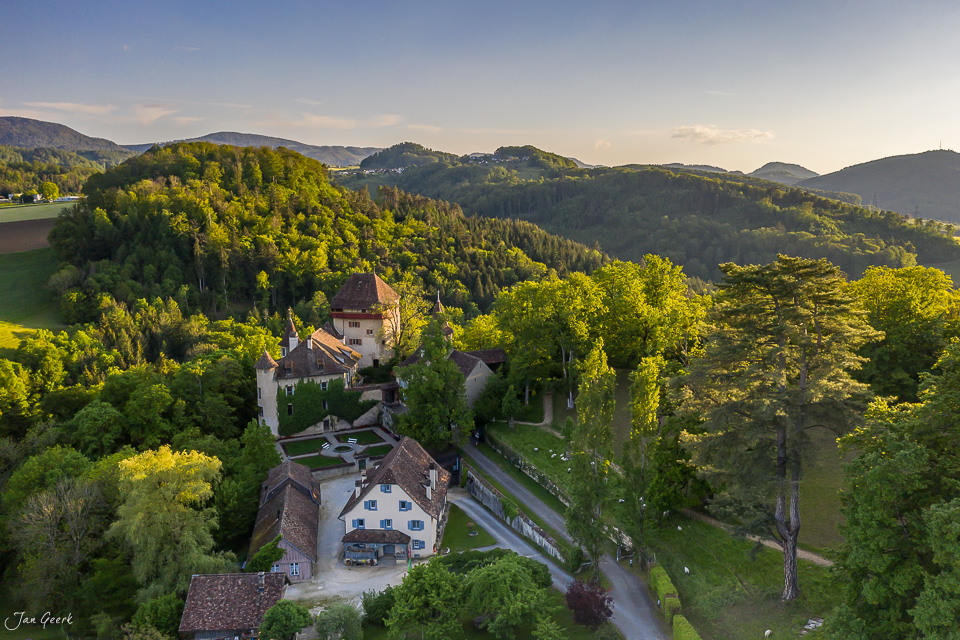 Schloss Wildenstein in Bubendorf von oben fotografiert, umgeben von grünen Wäldern in Abendlicht, Baselland Schweiz – Jan Geerk Fotograf Basel