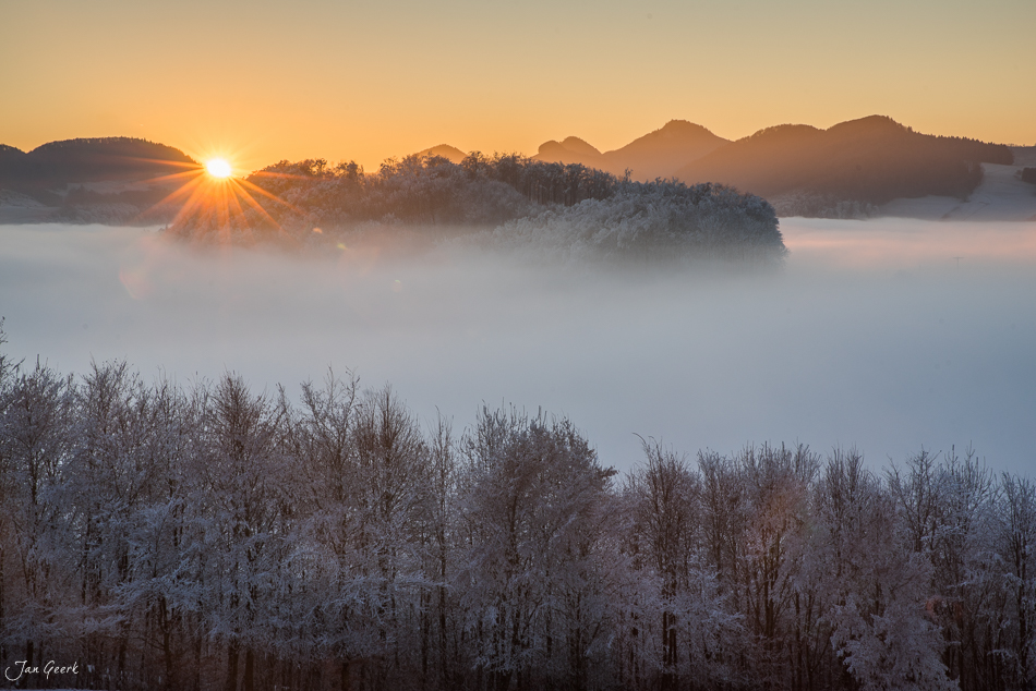 Winterlandschaft Wisenberg mit Nebelwelle, Sonnenaufgang über verschneiten Wäldern, Baselland Schweiz – Jan Geerk Fotograf Basel