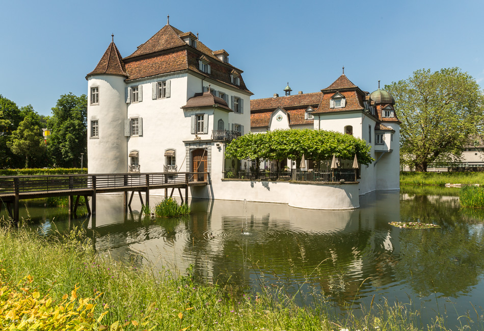 Wasserschloss Bottmingen im Frühling mit Spiegelung, grüne Wiese und Holzsteg, Baselland Schweiz – Jan Geerk Fotograf Basel