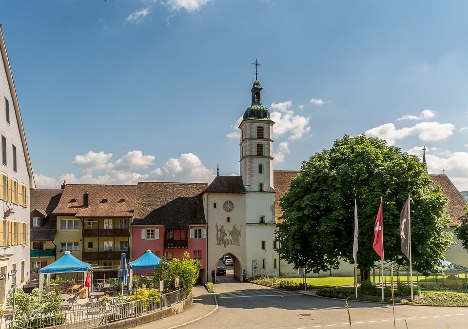 Stadttor mit grüner Kuppel, farbige Altstadt und blauem Himmel in Laufen Baselland Schweiz – Jan Geerk Fotograf Basel