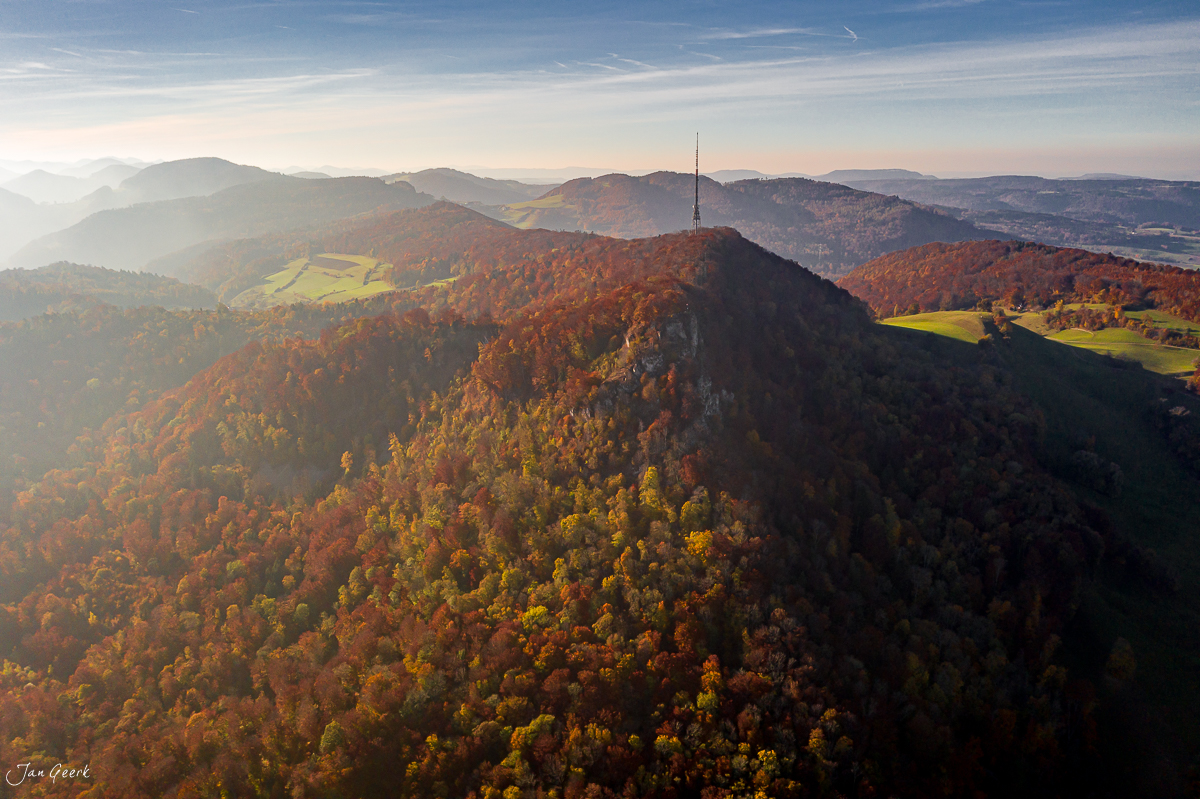 Herbstliche Berglandschaft mit Funkturm auf bewaldeten Hügeln, goldenes Licht, Nordwestschweiz – Jan Geerk Fotograf Basel