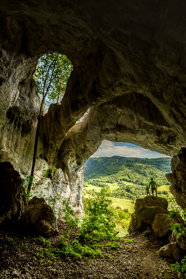 Höhle mit Ausblick auf grüne Jurawaldlandschaft im Frühling Welschenrohr Schweiz – Jan Geerk Fotograf Basel