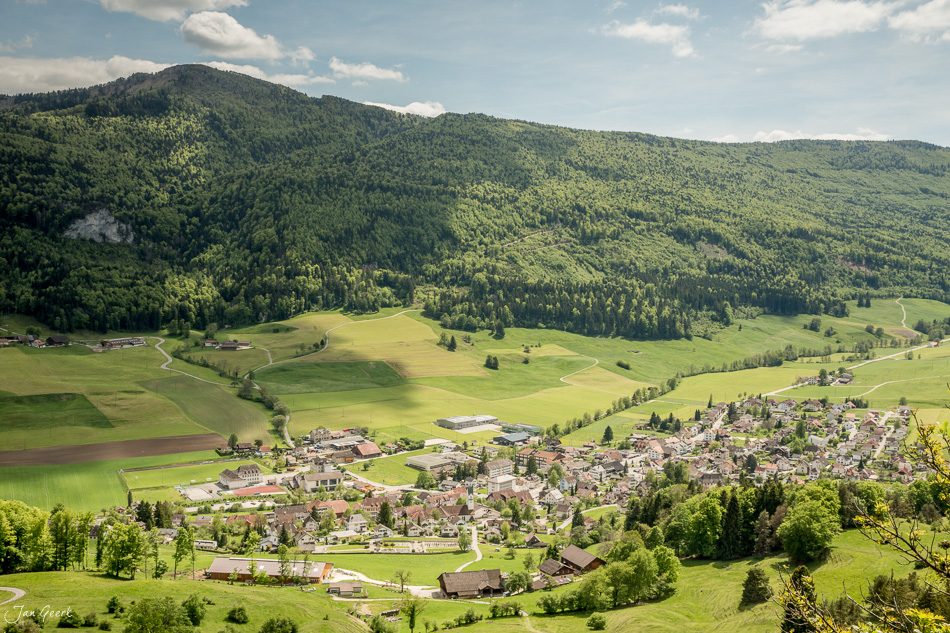 Luftaufnahme Welschenrohr mit grünen Wiesen, bewaldeten Hügeln und Dorfansicht im Frühling, Jura-Region Schweiz – Jan Geerk Fotograf Basel