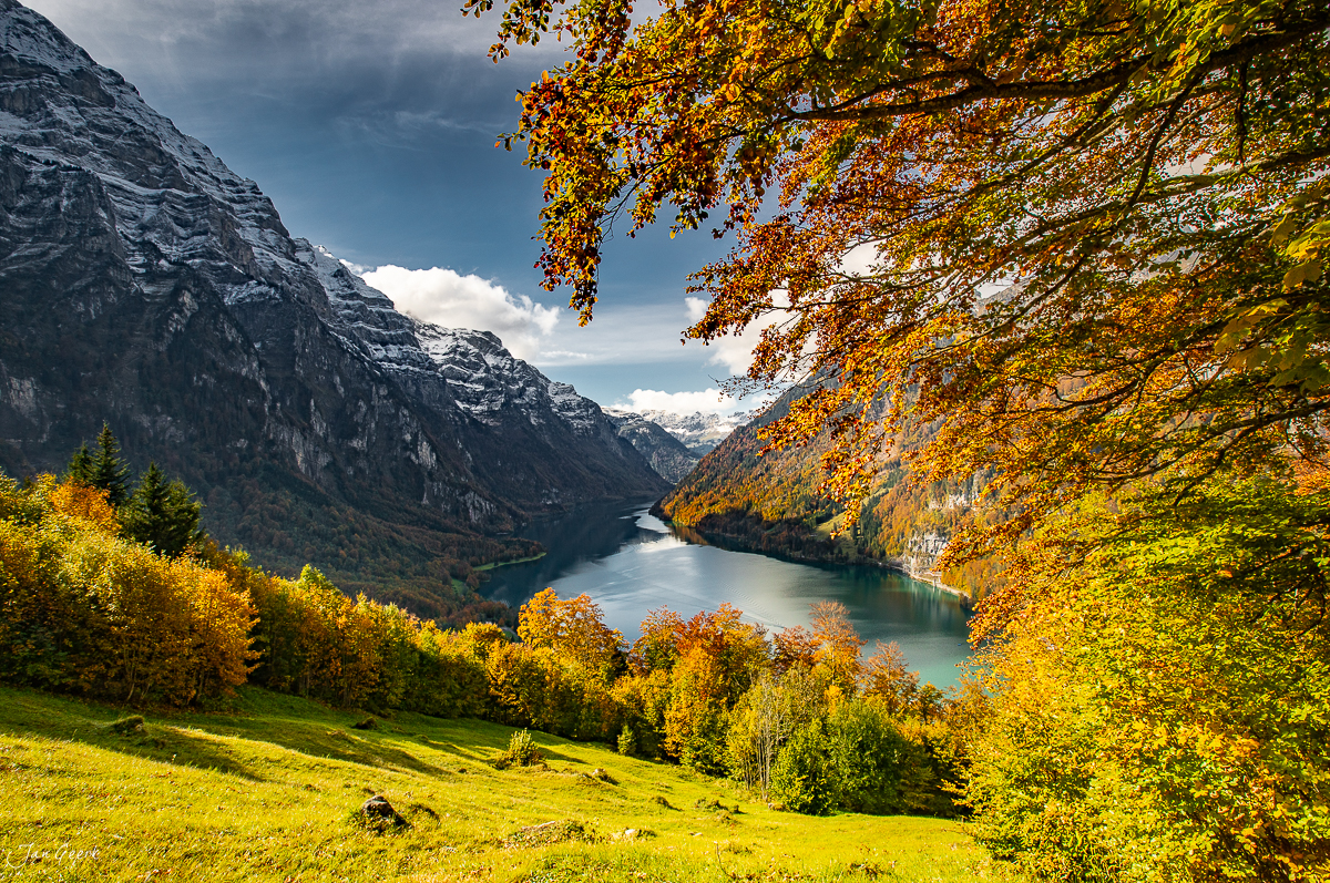 Herbstlicher Blick auf den Klöntalersee mit schneebedeckten Bergen, golden leuchtenden Laubbäumen und türkisblauem Wasser, Glarus Schweiz – Jan Geerk Fotograf Basel