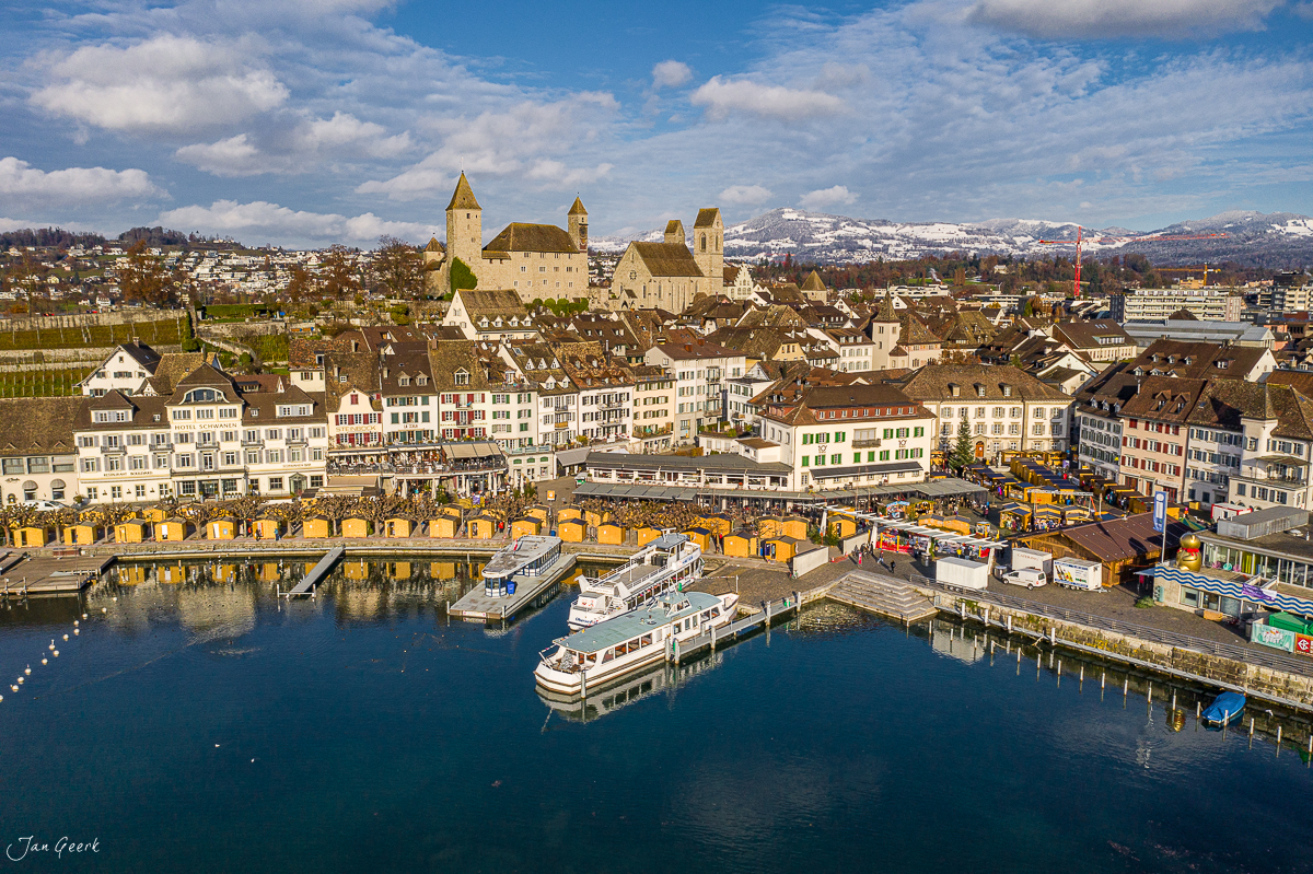 Luftaufnahme Rapperswil mit Schloss, farbigen Bootsplätzen und Seeufer bei Sonnenschein – Jan Geerk Fotograf Basel Schweiz