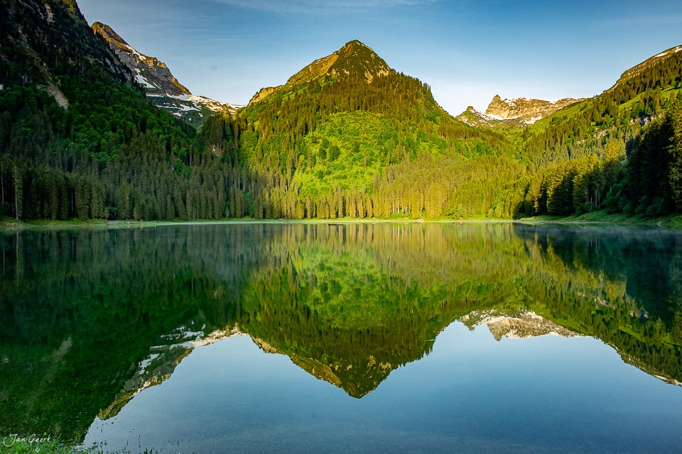 Spiegelglatter Bergsee mit Bergpanorama im Sommer, grüne Nadelwälder, Schweiz – Jan Geerk Fotograf Basel