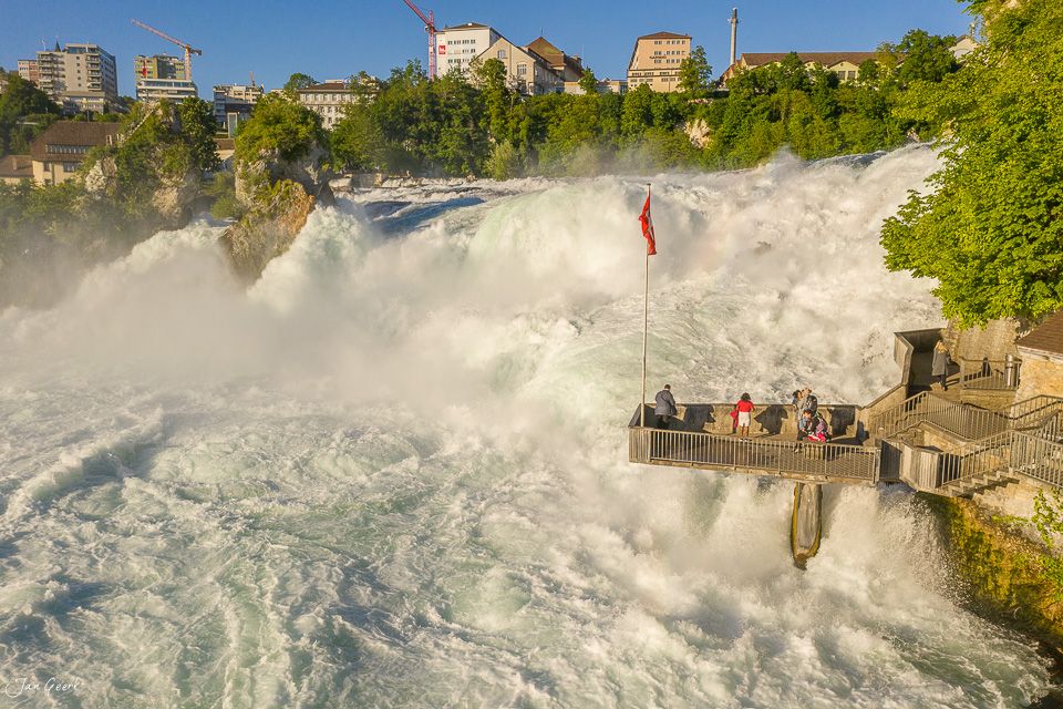 Rheinfall Schaffhausen mit tosenden Wassermassen, Besucherplattform und Schweizer Flagge bei Sonnenschein – Jan Geerk Fotograf Basel