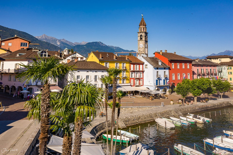 Ascona Hafenplatz mit farbigen Häusern, Kirchturm und Seebooten bei Sommersonne, Tessin Schweiz – Jan Geerk Fotograf Basel