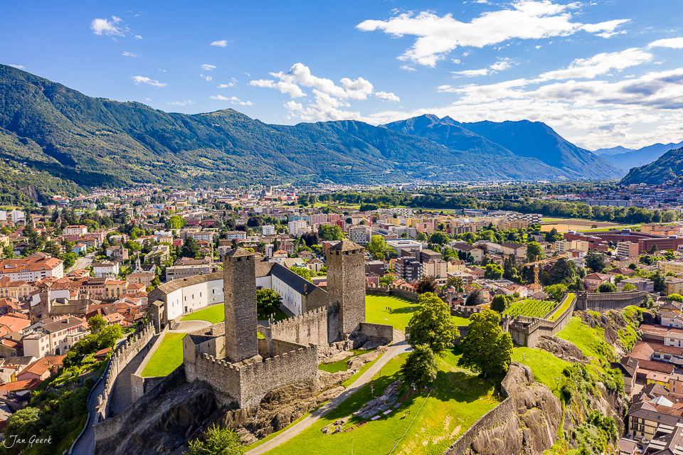 Luftaufnahme der mittelalterlichen Burgen von Bellinzona mit grünen Wiesen, Bergen im Hintergrund, Sommerstimmung im Tessin Schweiz – Jan Geerk Fotograf Basel