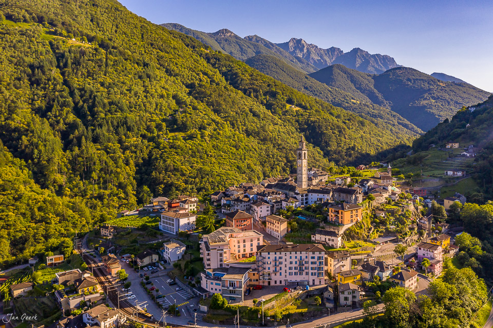 Luftaufnahme des Dorfes Intragna im Centovalli mit Kirchturm, umgeben von grünen Bergen im Sommer, Tessin Schweiz – Jan Geerk Fotograf Basel