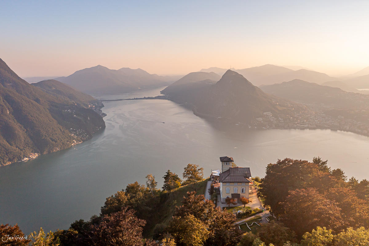 Luftaufnahme Lugano mit historischer Kirche, Alpenpanorama und Seelandschaft im Herbstlicht, Tessin Schweiz – Jan Geerk Fotograf Basel