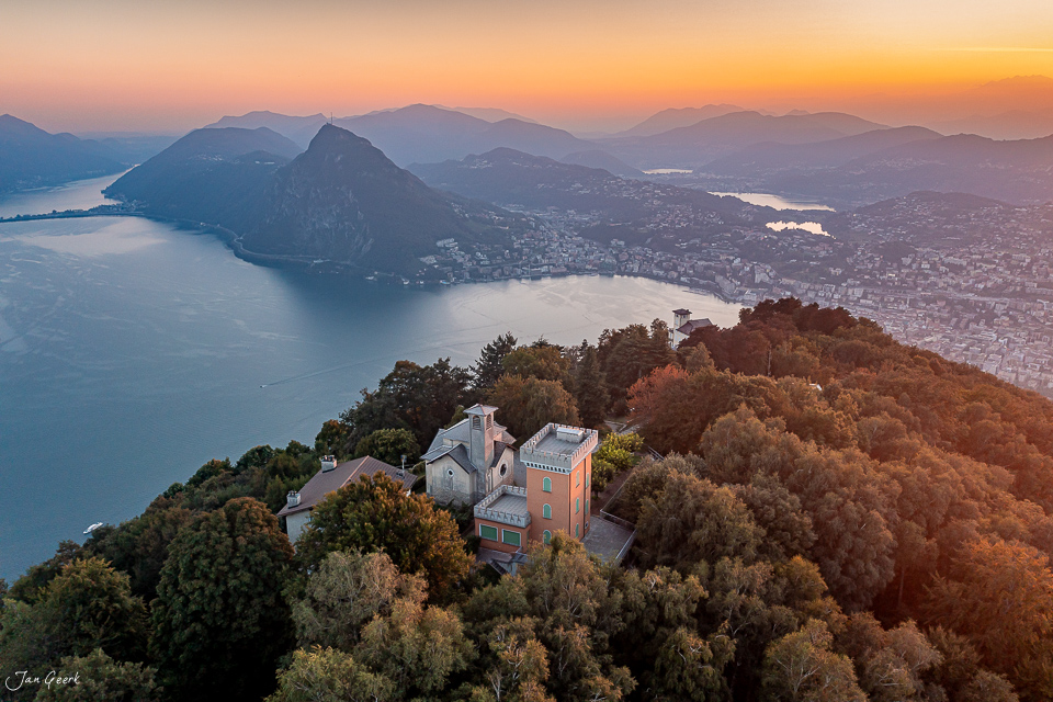 Luftaufnahme Schloss Lugano am Seeufer mit Herbstwald, Morgenlicht über dem Tessin Schweiz – Jan Geerk Fotograf Basel